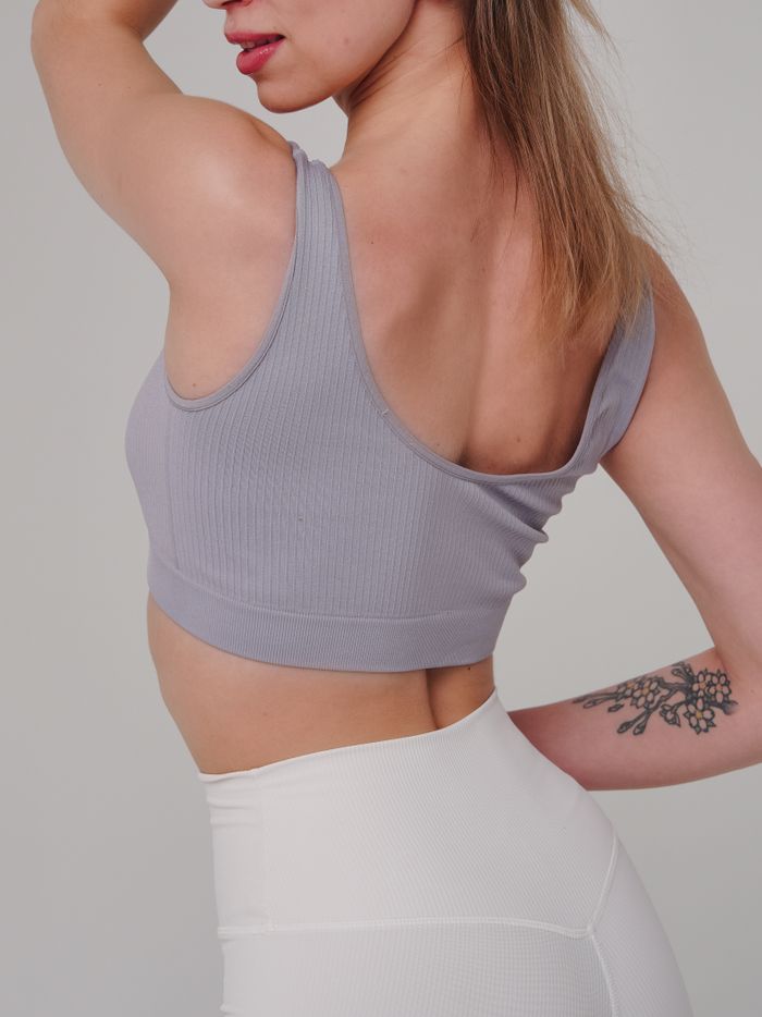 Stylish woman in gray top with arm tattoo posing for fashion shoot.