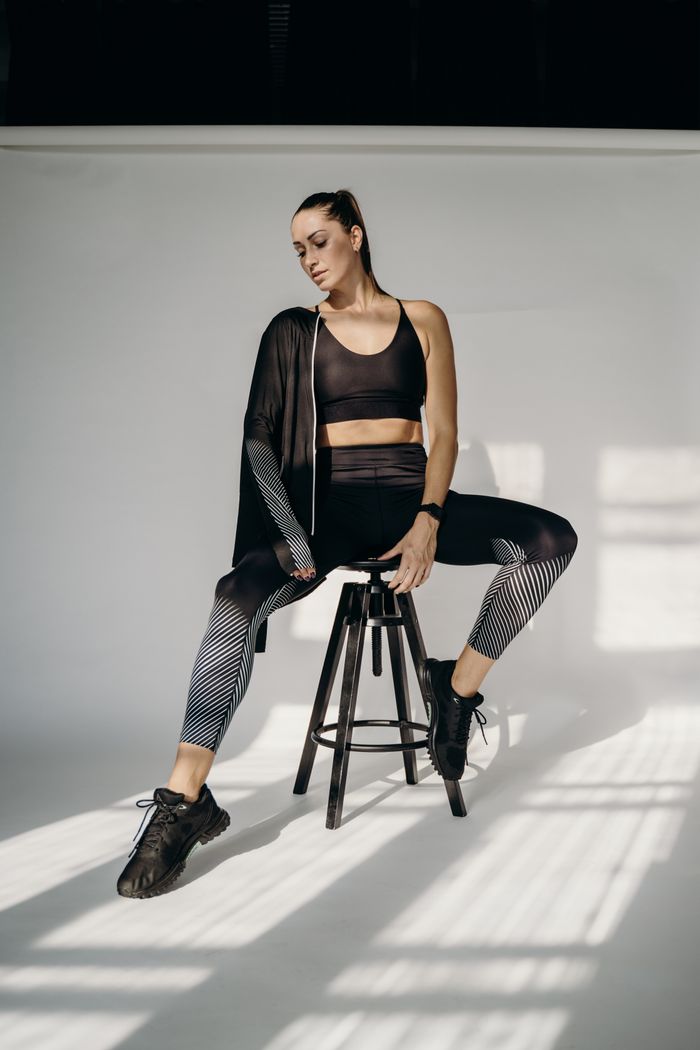 Confident woman in stylish activewear striking a pose in a well-lit studio setting.