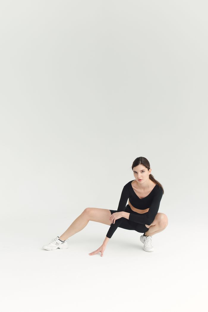 Fit woman in black athletic wear posing on white background in studio.